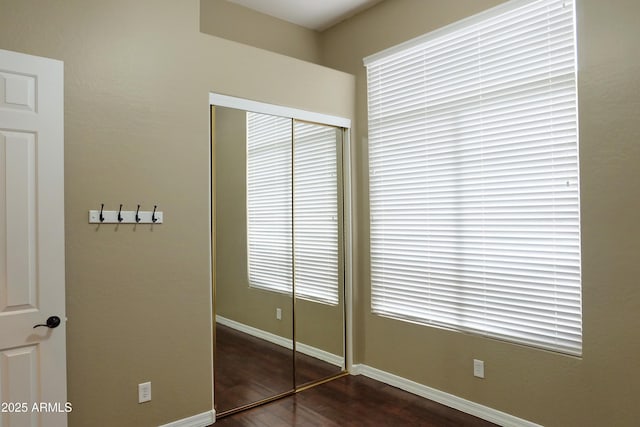 unfurnished bedroom with wood finished floors, a closet, and baseboards