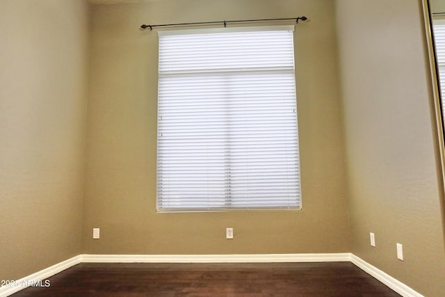 empty room featuring dark wood-style floors and baseboards