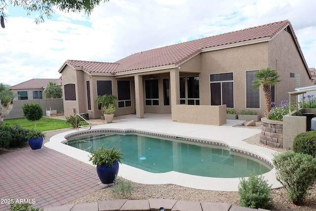 rear view of house featuring a tiled roof, a fenced in pool, stucco siding, and a patio area