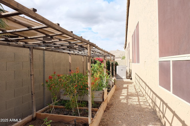 view of side of home featuring stucco siding, a vegetable garden, and fence