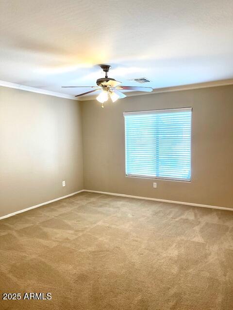 carpeted empty room with crown molding, baseboards, and ceiling fan