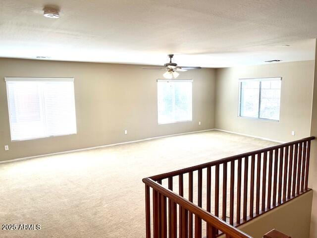 empty room featuring carpet, baseboards, and a ceiling fan