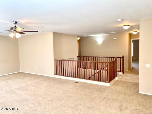 unfurnished room featuring light colored carpet, ceiling fan, and baseboards