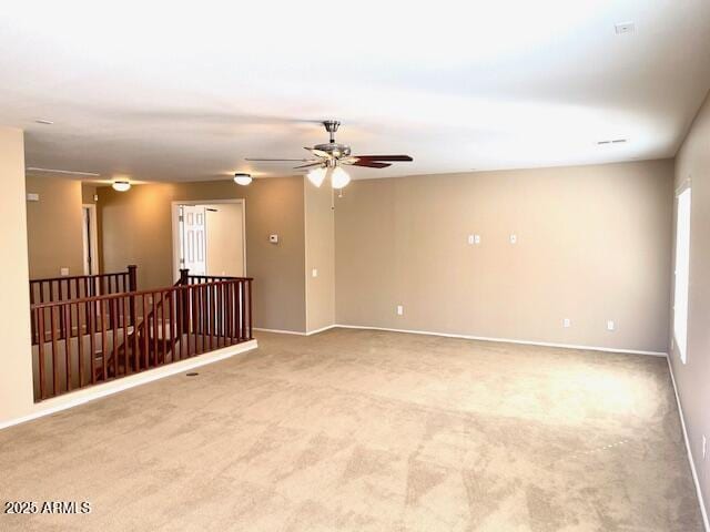 spare room with baseboards, a ceiling fan, and light colored carpet