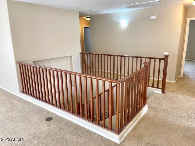 hallway with visible vents, carpet, an upstairs landing, and baseboards