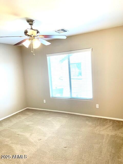 unfurnished room with light carpet, a ceiling fan, visible vents, and baseboards