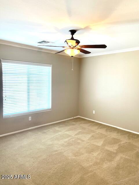 unfurnished room featuring light colored carpet, crown molding, visible vents, and baseboards