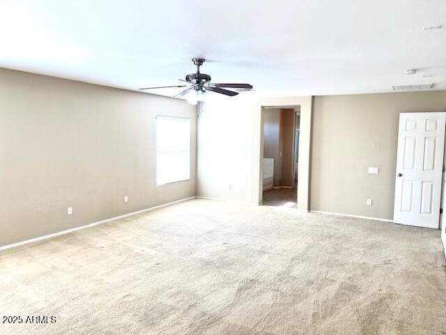 unfurnished bedroom featuring baseboards, a ceiling fan, visible vents, and light colored carpet