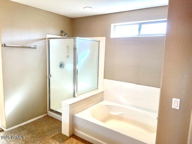 bathroom with a garden tub, a shower stall, and baseboards