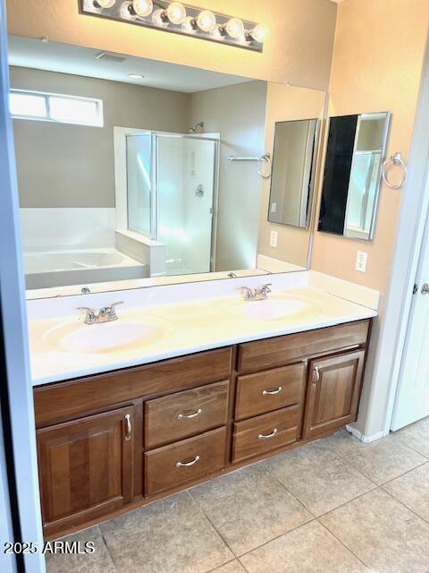 full bath with double vanity, a stall shower, tile patterned flooring, and a sink