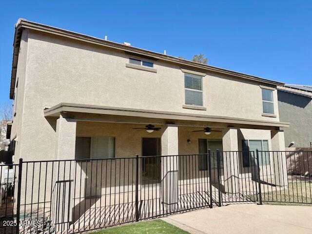 back of property with a fenced front yard, a ceiling fan, and stucco siding