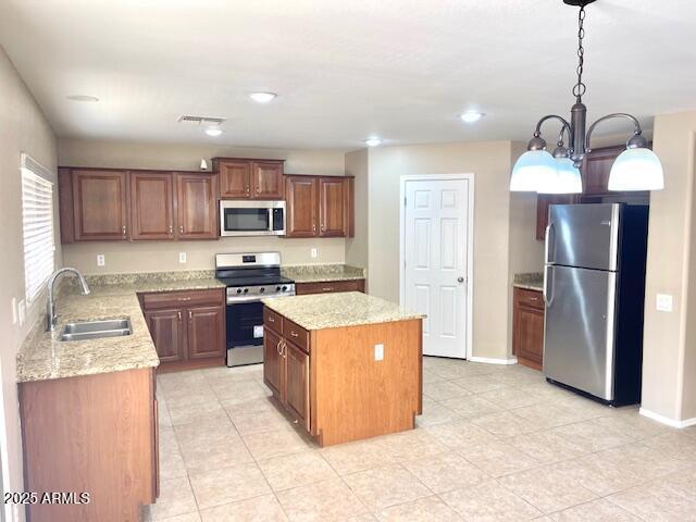 kitchen with light stone counters, decorative light fixtures, a center island, stainless steel appliances, and a sink