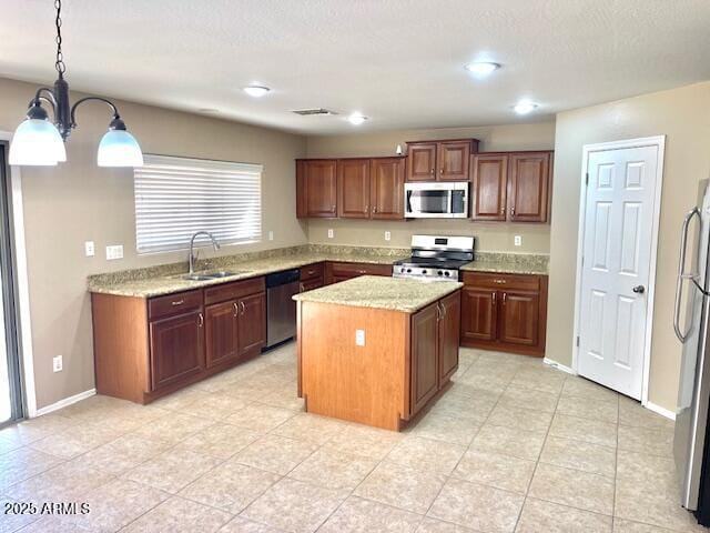 kitchen with appliances with stainless steel finishes, a center island, hanging light fixtures, light stone countertops, and a sink