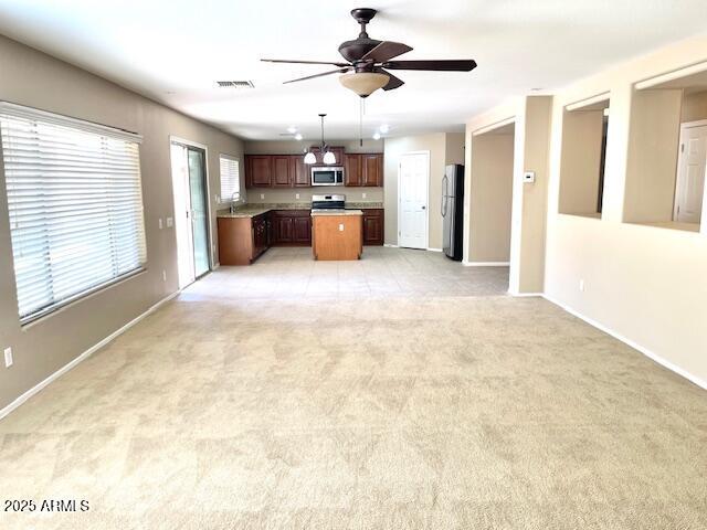 kitchen with light carpet, stainless steel appliances, open floor plan, light countertops, and a center island