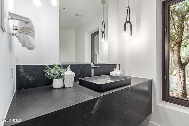 bathroom with tasteful backsplash, visible vents, and a sink