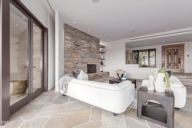 living room with french doors, a fireplace, stone tile flooring, and recessed lighting