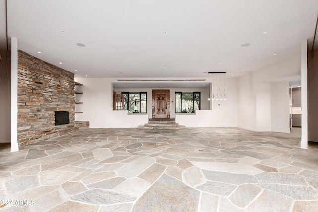 unfurnished living room featuring a fireplace, stone floors, and recessed lighting