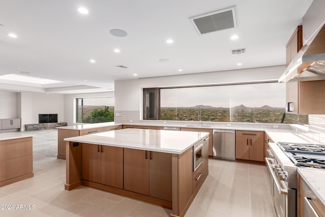 kitchen with a wealth of natural light, a fireplace, stainless steel appliances, a mountain view, and a kitchen island