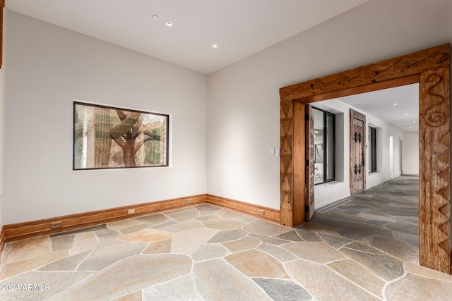 unfurnished room with baseboards, recessed lighting, and stone floors