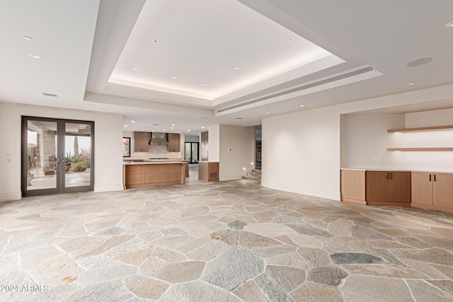 unfurnished living room with french doors and a raised ceiling