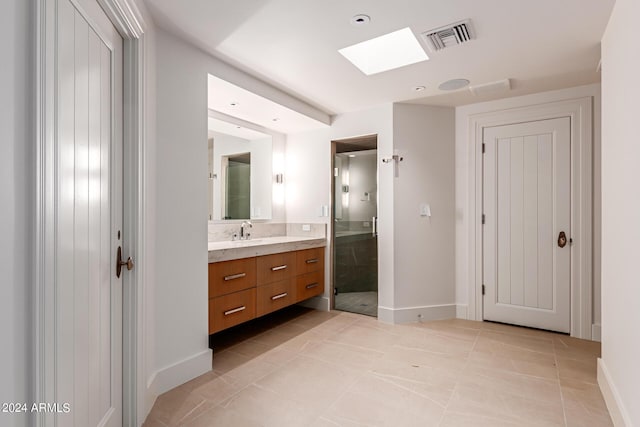 bathroom with tile patterned flooring, vanity, a skylight, and walk in shower