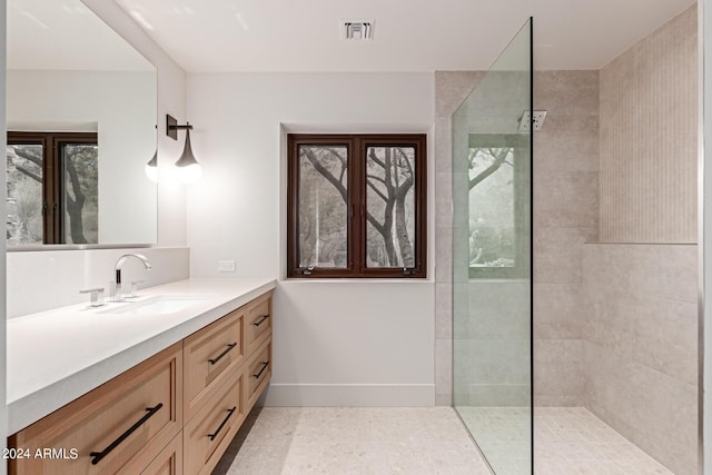 bathroom featuring a walk in shower, vanity, visible vents, and baseboards