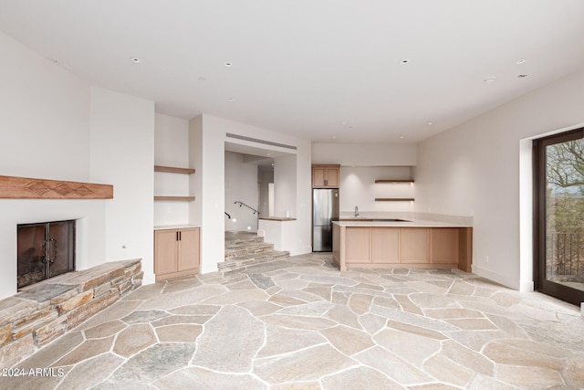 unfurnished living room with stone finish flooring, a fireplace with raised hearth, baseboards, and stairs