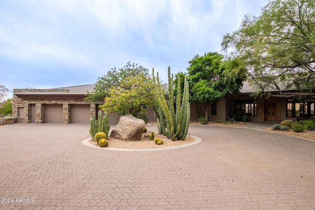 view of front facade featuring stone siding, decorative driveway, and stucco siding