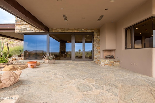 view of patio with an outdoor stone fireplace and french doors