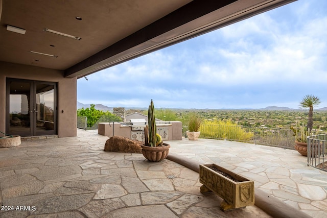 view of patio with french doors, fence, and a mountain view