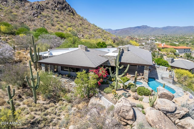 back of property featuring stone siding, a tiled roof, a patio area, and a mountain view