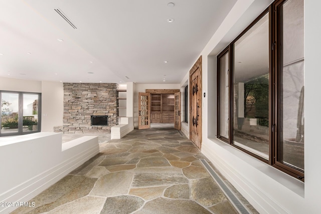 hallway featuring stone tile floors, visible vents, baseboards, and recessed lighting