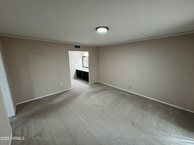 empty room featuring crown molding, carpet, visible vents, and baseboards