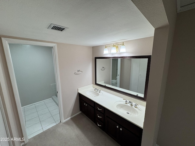 full bathroom with a textured ceiling, double vanity, visible vents, and a sink