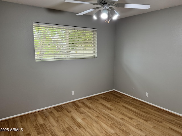 unfurnished room with wood finished floors, a ceiling fan, and baseboards