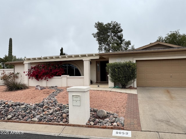 ranch-style home featuring stucco siding, an attached garage, and concrete driveway