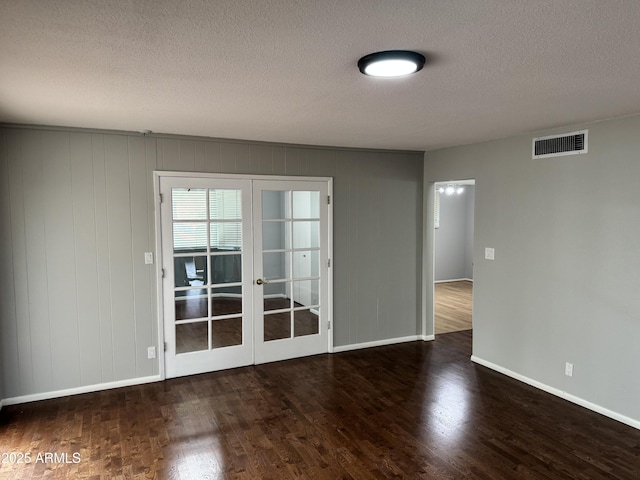 spare room featuring visible vents, baseboards, wood finished floors, and french doors