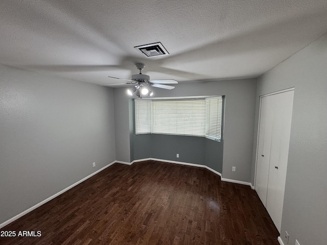 unfurnished bedroom featuring a ceiling fan, baseboards, wood finished floors, visible vents, and a textured ceiling