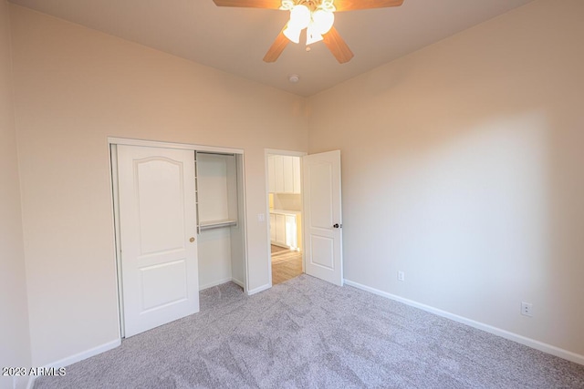 unfurnished bedroom with ceiling fan, light carpet, and a closet