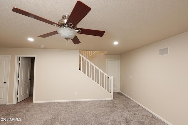 basement featuring light colored carpet and a textured ceiling