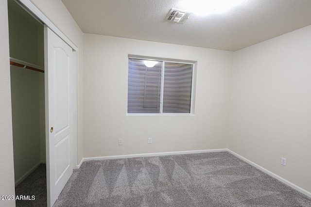 unfurnished bedroom with carpet flooring, a closet, and a textured ceiling