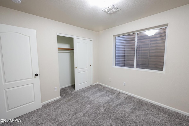 unfurnished bedroom featuring carpet flooring, a textured ceiling, and a closet