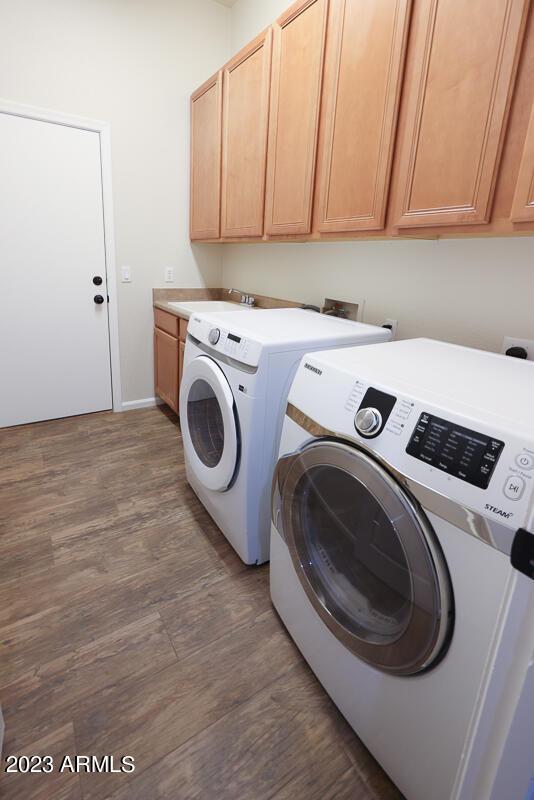 laundry room with separate washer and dryer, dark wood-type flooring, cabinets, and sink