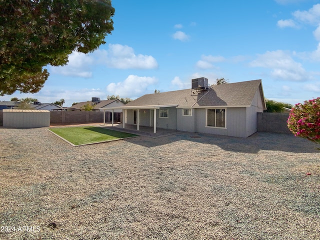 rear view of property with a lawn, a patio area, and central air condition unit