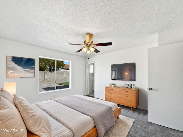 bedroom featuring ceiling fan, dark carpet, and a textured ceiling