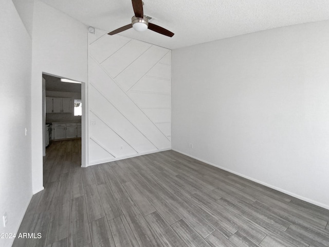 spare room featuring dark hardwood / wood-style floors, ceiling fan, a textured ceiling, and a high ceiling