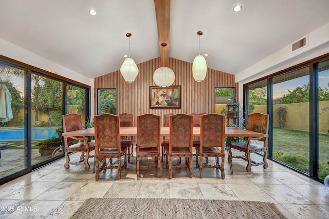 dining space with wood walls, beamed ceiling, and a healthy amount of sunlight