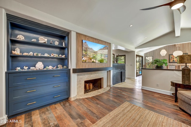 living room with ceiling fan, dark wood-type flooring, a fireplace, vaulted ceiling with beams, and built in shelves