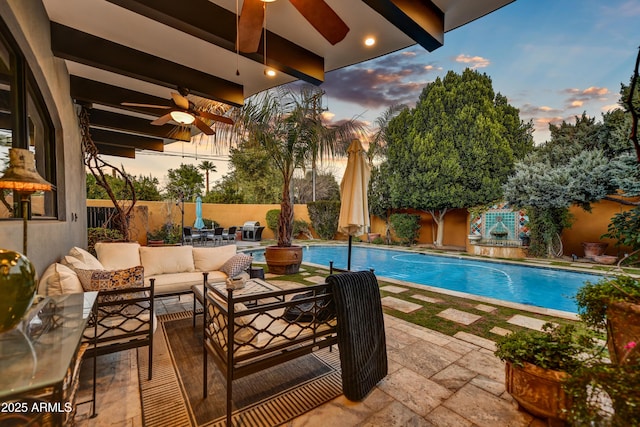 pool at dusk featuring ceiling fan, outdoor lounge area, and a patio