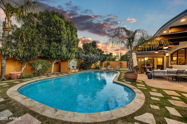 pool at dusk featuring a patio area and an outdoor living space